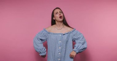 Bir kadın canlı pembe bir arka fonun önünde duruyor, şık, omuzsuz bir kıyafet sergiliyor. Çeşitli duygular sergiliyor, jestlerle büyüleyici bir hikaye aktarıyor..