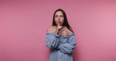 Bir insan neşeli bir şekilde canlı pembe bir arkaplan önünde şşşş jesti yapar, neşeli bir ruh hali ve çekici bir ifade sergiler. Günlük kıyafet eğlenceli atmosfere katkı sağlıyor..