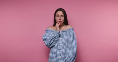 Çekici bir kadın pembe arka planda dikiliyor ve kameraya bakıyor.