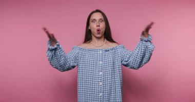 Mavi ve beyaz omuzlu genç bir kadın vitrinleri kontrol etti enerjik bir dans gösterisi. Neşeli ifadesi ve jestleri parlak pembe bir zemin ile canlı bir atmosfer yaratıyor..