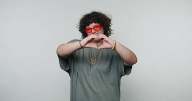 Bireysel coşkuyla işaret dilini gösteriyor, açık jestler ve çekici bir gülümsemeyle mesaj iletiyor, çağdaş bir ortamda canlı bir kişilik sergiliyor..