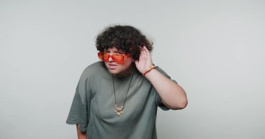 Bu ilgi çekici an kıvırcık saçlı, parlak güneş gözlüğü takan, minimalist stüdyo ortamında yaratıcı fikirleri dikkatle dinleyen birini yakalıyor..