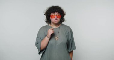 Bireyler, büyük beden kıyafetler ve renkli aksesuarlarla benzersiz bir moda anlayışı sergilerken kapalı alandaki minimalist bir ortamda derin derin derin düşünür..