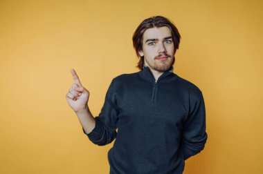 Sırıtan ve sarı arka planda parmağını önde gösteren genç adamın portresi.