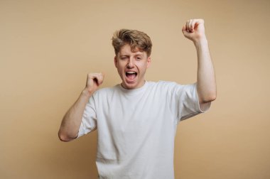 Bej arka planda coşkuyla dolu, heyecan dolu bir anda genç bir adamın enerjik bir tezahüratı.