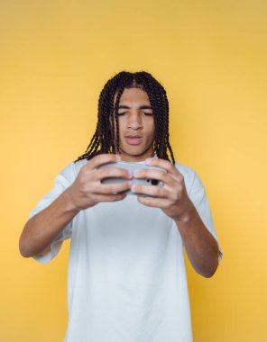 Genç adamın portresi yoğun bir şekilde bir video oyunu oynamaya odaklanmış, sarı arka planda oyun kültürünün ve heyecanın özünü yakalıyor.