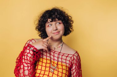 Düşünceli genç bir kadının portresi, dalgın bir poz sergiliyor, sarı arka planda bir neşe işareti var.