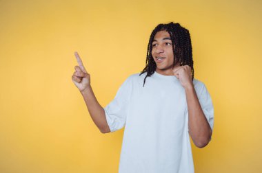 Sarı arka planda zafer kazandıktan sonra heyecan ve mutluluk sergileyen genç bir adamın portresi.