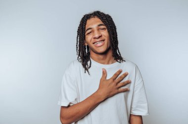 Genç adamın portresi parlak bir gülümseme, beyaz arka planda neşe ve sıcaklık sergiliyor.