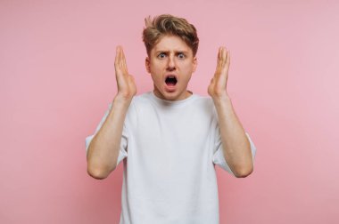 Şok olmuş bir gencin portresi ellerini kaldırır. Pembe arka planda şaşkınlık ya da inançsızlığı ifade eder.