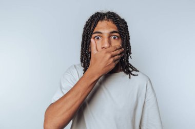 Şaşırmış genç adamın portresi, beyaz arka planda şok ve güvensizlik iletir.