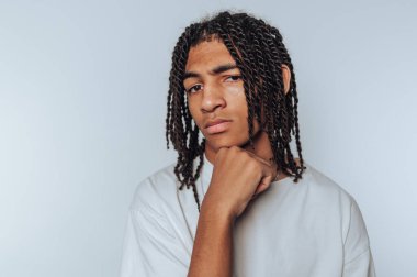 Genç bir adamın portresi, elini beyaz arka planda dinlendirirken ciddi bir ifadeyle derin derin düşünürken gösterilir.