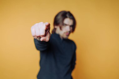 Özgüvenli bir şekilde genç bir adamın portresi kararlılığı gösterir ve sarı arka plana odaklanır.