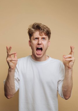 Umudunu ve beklentilerini bej arka planda coşkulu bir ifadeyle ifade eden genç bir adamın portresi.