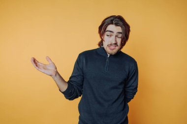 Genç bir adamın portresi kaldırılmış eller ve şaşkın bir bakışla duruyor, sarı bir duvara karşı açık yüreklilikle inançsızlığını sorguluyor ya da ifade ediyor..