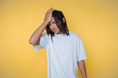 Kafasını tutan genç adamın portresi, sarı arka planda yorgunluk ya da stres taşıyor.