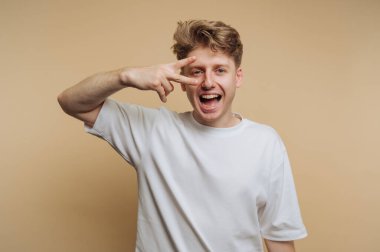 Genç mutlu bir adamın portresi, bej arka planda neşeli ve kaygısız bir tavır sergiliyor.