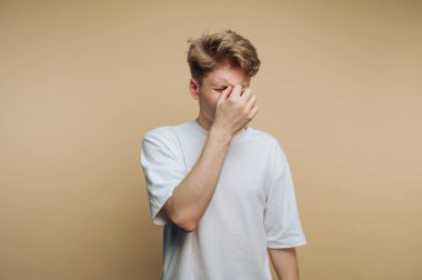 Genç adamın portresi, bej arka planda bir anlık stres rahatlama portresi çizerken görülüyor.