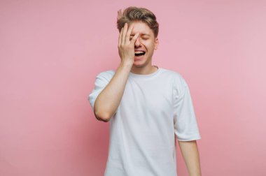 Sıkıntılı genç adamın portresi, pembe arka plandaki hayal kırıklığının ve duygusal mücadelenin derinliğini resmeden yüzünü hüsran içinde gizler.