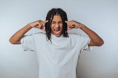 Genç adamın portresi, beyaz arka planda dinamik bir duruşta hayal kırıklığını gösteren anlamlı bir duygusal patlama sergiliyor.