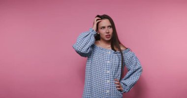 Pembe arka planda neşeli jestler yapan canlı mavi elbiseli genç bir kadının görüntüleri.