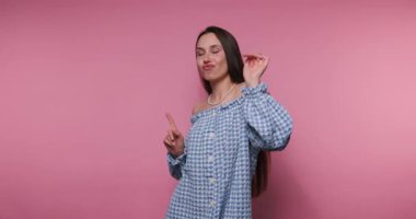 Genç bir kadının görüntüleri pembe arka planda neşe ve zarafetle dolu hoş bir dans hareketi sergiliyor.