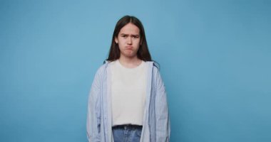 Genç kızın görüntüsü kasvetli ve ciddi bir ifadeyle mavi arka planda bir anlık yansıma ve ciddiyet gösteriyor.