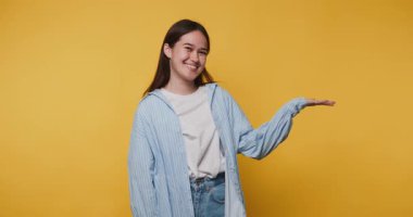 Genç, neşeli bir kadının elini uzatırken gülümsemesi, sarı arka planda etkileşime davetiye çıkarıyor.