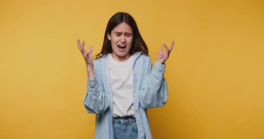 Genç bir kadının, yüz ifadesi ve sarı arka plandaki el hareketleriyle hayal kırıklıklarını aktardığı görüntüler.