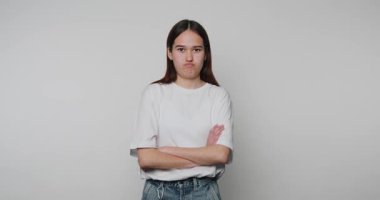 Genç bir kadının görüntülerinde kolları çaprazlanmış bir şekilde hayal kırıklığı ve bej arka planda tefekküre dalma duyguları ön plana çıkıyor.