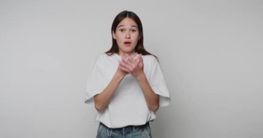 Genç bir kadının bej arka planda elleri ile ağzını kapattığı görüntüler şaşırmış görünüyor.