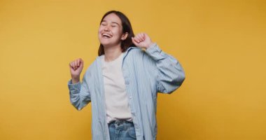 Dans eden genç bir kadının sarı arka planda saf neşe ve heyecan sergilediği görüntüler.