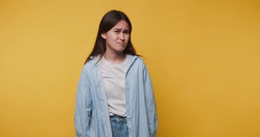 Sarı arka planda duran genç bir kadının görüntüsü mutsuz bir ifade sergiliyor.