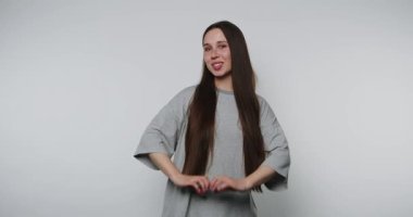 Genç bir kadının mutlu bir şekilde dans ettiği ve açık arkaplanda gri bir kıyafetle kutlama yaptığı görüntüler.
