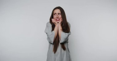 Genç bir kadının kaygısını ve endişesini açık arkaplanda dudağını ısırırken gösteren görüntüler.