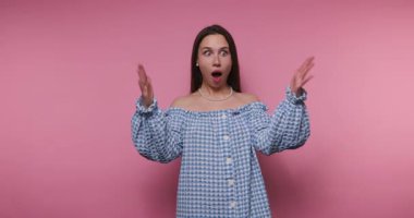 Endişeli genç bir kadının ellerini kullanarak pembe arka planda mavi kareli bir kıyafet giydiğini gösteren bir uyarı görüntüsü.