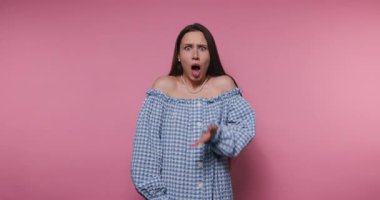 Elleriyle yüzünü gizleyen genç bir kadının görüntüsü pembe arka plandaki duygu yoksunluğunu simgeliyor.