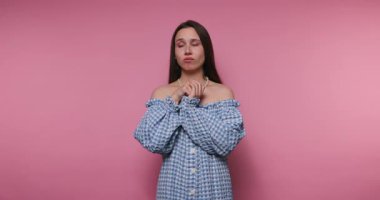 Genç bir kadının görüntüsü, düşünceli bir ifade ve pembe arka planda moda anlayışı sergiliyor.