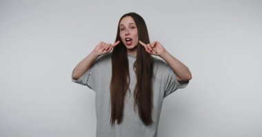 Genç bir kadının görüntüsü, yanaklarını parmaklarıyla dürterek neşeli bir yüz yapar. Hafif arka planda neşeli ve neşeli bir kişilik sergiler.