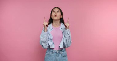 Genç bir kadın kişisel gelişim ve kendine güvenle ilgili fikirlerini ifade ediyor. Parlak pembe bir arkaplan önünde durup, izleyicilere mesajını iletirken tutkuyla jest yapıyor..