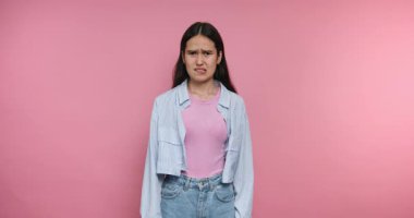 Bir kadın pembe arka planı olan parlak bir stüdyoda duruyor. İfadeleri üzüntüden kafa karışıklığına ve sonunda da mutlu olmaya dönüşüyor..