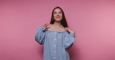 Neşeli bir kız pembe bir arka plana karşı kendini çekici bir şekilde ifade eder. Neşeli hareketleri ve mutlu gülüşü eğlenceli bir atmosfer yaratıyor. Bu neşeli anın tadını çıkar..