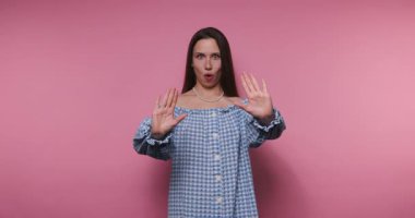 Mavi kareli bluzlu bir kadın pembe arka planda farklı duygular gösterir. Anlamlı jestleri şaşkınlık, hayal kırıklığı ve neşe veriyor..