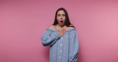 Bir kadın, canlı pembe bir arkaplan karşısında şaşkınlık ve şaşkınlık gibi çeşitli tepkiler gösterir. Neşeli duyguları etrafındaki renklere ve atmosfere neşe katıyor..