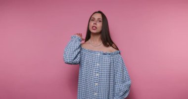 Genç bir kadın parlak pembe bir arka plana karşı çeşitli jestler ve yüz ifadeleri sergiliyor. Hareketleri duyguları açık ve yaratıcı bir şekilde aktarıyor, izleyicileri tamamen cezbediyor..