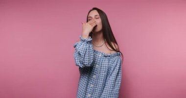 Mavi kareli gömlekli bir kız pembe bir duvara karşı çeşitli duygular gösterir. Öpüşüyor, el sallıyor ve neşeli bir gülümseme sergiliyor. Eğlenceli bir atmosfer yakalıyor..