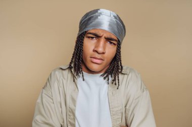 Örgülü saçı ve gümüş sarısı olan genç bir birey kafa karıştırıcı bir ifade sergiliyor. Sade ve nötr bir arkaplan oluşturarak çarpıcı bir kontrast oluştururlar..