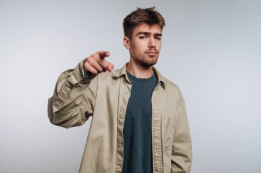 Stüdyoda sıradan kıyafetler giymiş genç bir adam var. Kamerayı işaret ederken kendine güveni tamdır. Çekici bir an yaratır..