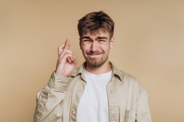 Genç bir adam umut dolu bir ifadeyle ayakta duruyor, şans diliyor ve gülümsüyor. Açık renk bir gömlek giyiyor ve rahat bir atmosferi var..