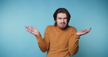 Genç adamın bej arka planda ellerini göğsünün yakınına koyarken sevinç ve heyecanı ifade eden görüntüleri.